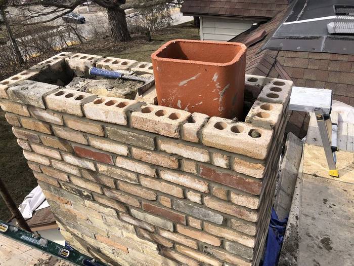Chimney rebuild in progress showing clay flue tile and new block and brick courses