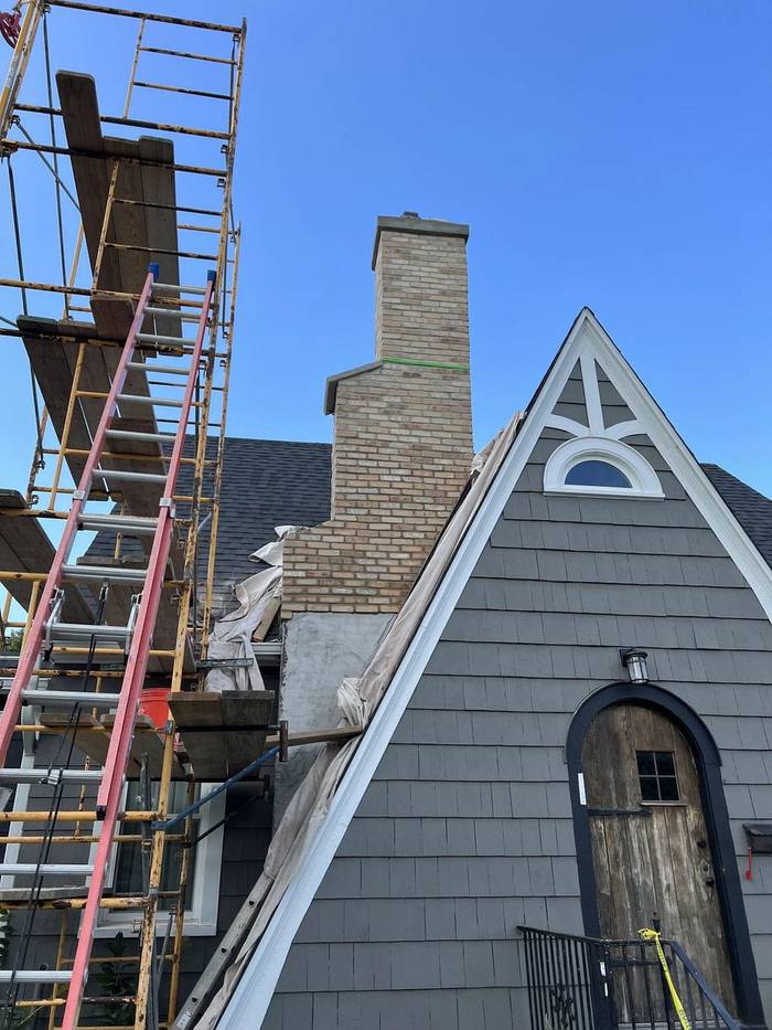 Chimney being re-wrapped in thin brick, scaffolding up, work in progress