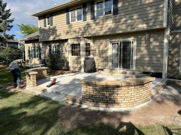 Backyard patio with a curved brick seating wall and steps, built by Watertight Masonry