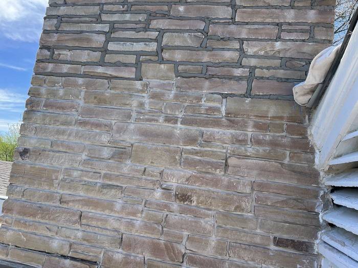 Restored stone veneer chimney with clean, matched mortar joints, by Watertight Masonry